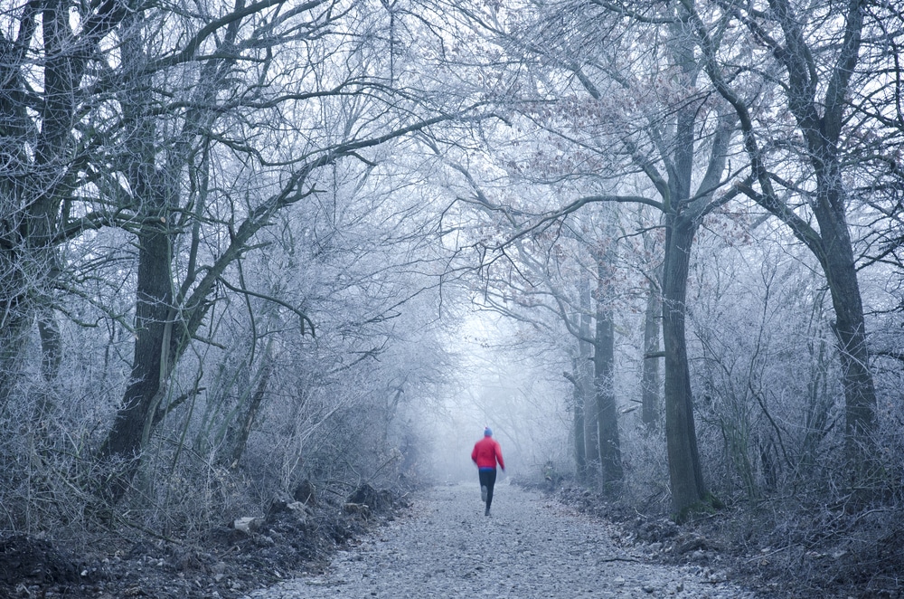 Man-running-along-forested-path-in-winter-with-winter-running-gear