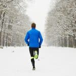 Man-running-down-snow-covered-path