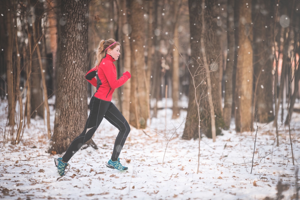 Woman-running-through-the-woods-in-the-snow-wearing-winter-running-shoes