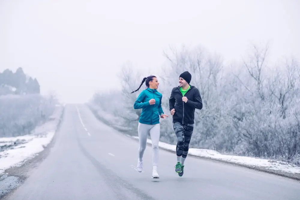 Young-couple-running-down-the-road-in-the-winter