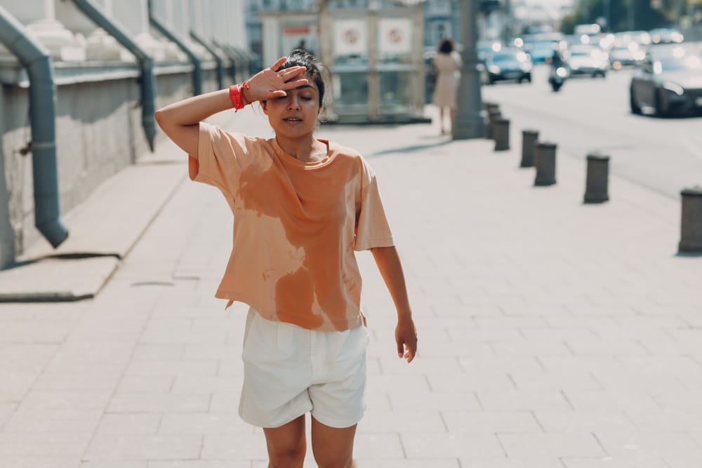 Young-Indian-woman-in-sweaty-t-shirt-wiping-her-forehead-while-running-in-the-heat