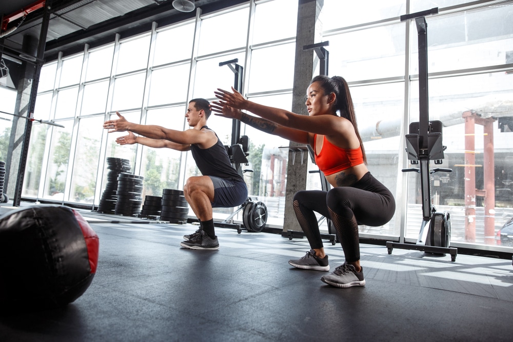 Man-and-woman-doing-squats-in-gym