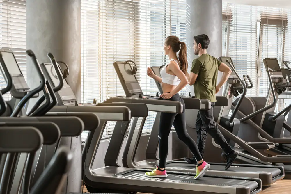 Man and woman running together on treadmills in gym
