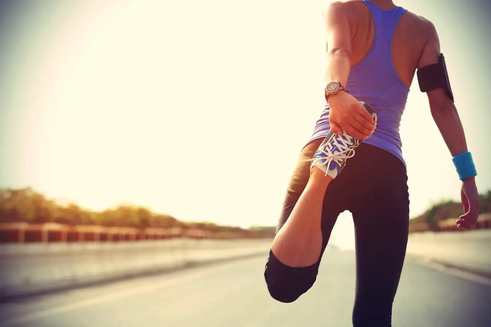 Young-athletic-woman-stretching-on-roadside-before-a-run
