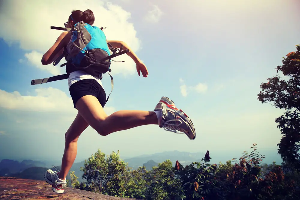 Young-woman-running-on-trail-while-wearing-running-backpack