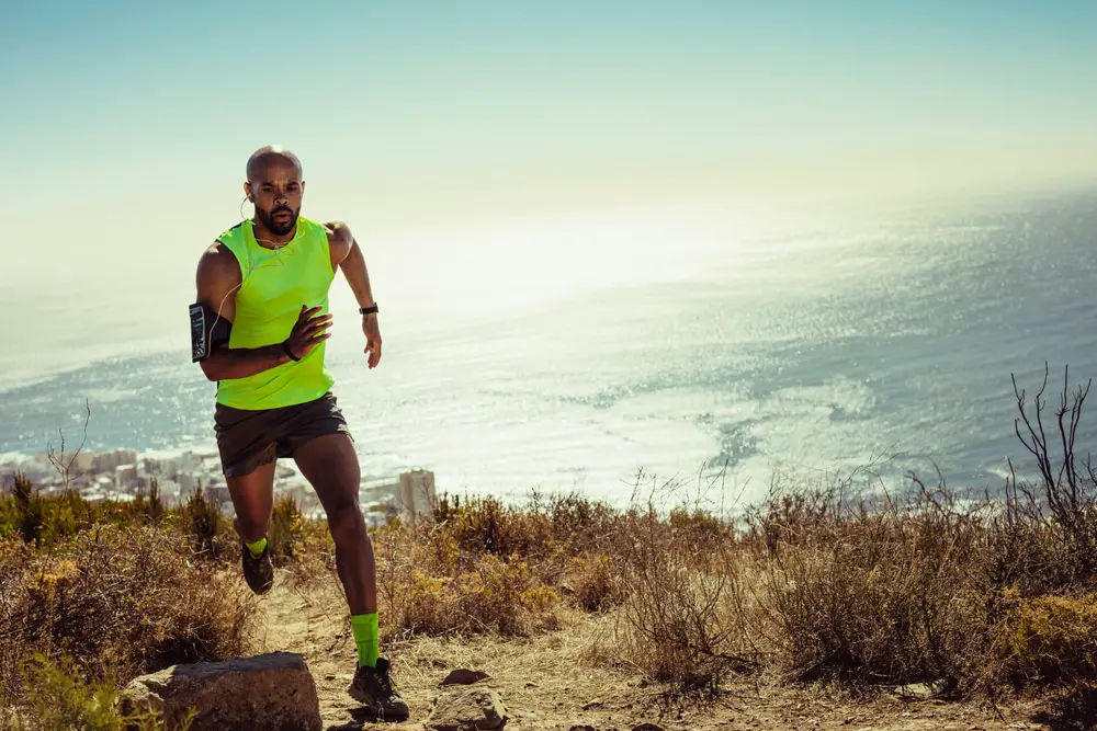Man in shorts and tank top sprinting up hillside